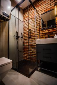 a bathroom with a glass shower and a brick wall at Apartament Piastowska No.6 in Olsztyn