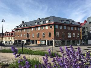 a large brick building on a street with purple flowers at Karlskrona H&H in Karlskrona