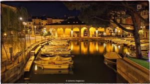 un gruppo di barche ormeggiate in un canale di notte di Hotel Piroscafo a Desenzano del Garda