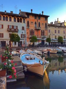 un gruppo di imbarcazioni ormeggiate nell’acqua vicino agli edifici di Hotel Piroscafo a Desenzano del Garda