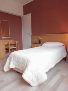 un grande letto bianco in una camera da letto con pavimento in legno di Hotel Mirella e Ristorante Bar Don Bacco a Orsago
