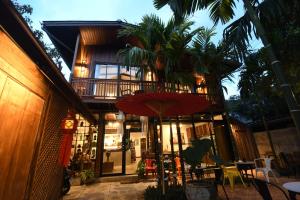 uma casa com uma varanda e um guarda-chuva vermelho em The Eight Ratvithi House em Chiang Mai