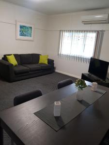 ein Wohnzimmer mit einem Tisch und einem Sofa in der Unterkunft Canberra Ave Villas in Queanbeyan