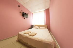 a pink bedroom with a bed with towels on it at Hotel Chaika in Barnaul