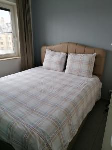 um quarto com uma cama com um cobertor xadrez e uma janela em Apartment Franky em Oostende