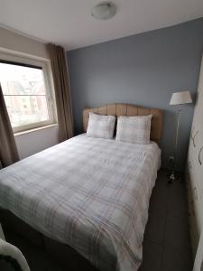 um quarto com uma cama com lençóis brancos e uma janela em Apartment Franky em Oostende