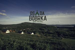 a sign on top of a green hill with trees at Osada Bóbrka nad Soliną in Solina