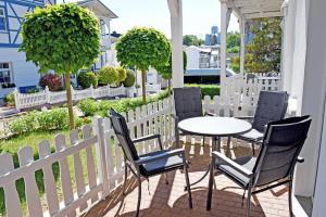 a table and chairs on a porch with a white fence at Ferienappartement mit Ostseeblick in Göhren