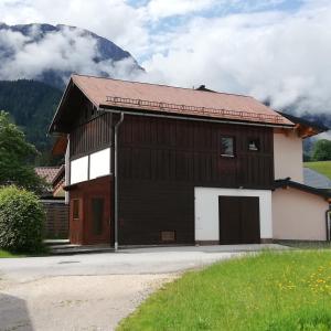 a brown and white building with a mountain in the background at Gaestehaus-Russegger in Abtenau