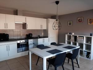 a kitchen with white cabinets and a table and chairs at Panda Parc Appartment proche Pairi Daiza-Shape-Nato in Lens