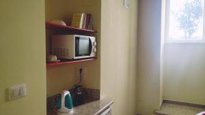 a kitchen with a microwave on a shelf next to a window at B&B Relax in Meta