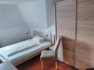 a bedroom with a bed and a chair at Hotel Rüstersieler Hof in Wilhelmshaven