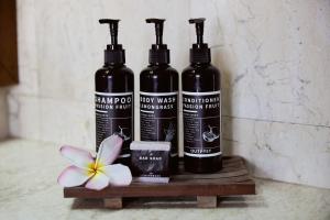 three bottles of wine on a wooden shelf with a flower at Outpost Ubud Nyuh Kuning in Ubud +25 photos