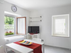 een witte woonkamer met een tafel en een tv bij Appartamento Ai Crocus in Cesclans