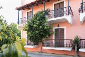 un edificio rosa con balconi e un albero di Socrates studio a Laganas