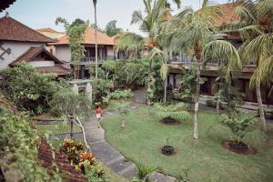 a woman walking through a garden in front of a building at Outpost Ubud Nyuh Kuning in Ubud
