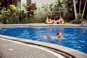 a child swimming in a swimming pool with two women at Outpost Ubud Nyuh Kuning in Ubud