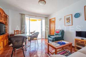 - un salon avec une table, des chaises et une télévision dans l'établissement Apartamento en Edificio Torresol, 1ª linea de playa en Nerja, à Nerja