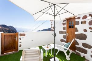 Un patio con una mesa y sillas y una sombrilla. en TenoHomes The Sunset Escape in Carrizales, Masca, en Buenavista del Norte 52 fotos más
