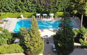 - une vue sur la piscine bordée d'arbres dans l'établissement Le Grand Hôtel - Domaine De Divonne, à Divonne-les-Bains