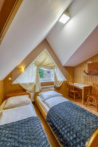 dwa łóżka w pokoju ze stołem i oknem w obiekcie Pokoje Gościnne Grzybek w Poroninie