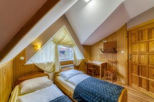 2 łóżka w pokoju z biurkiem i oknem w obiekcie Pokoje Gościnne Grzybek w Poroninie