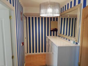 ein Bad mit blau und weiß gestreiften Wänden und einem Spiegel in der Unterkunft Residencia Compostela in Santiago de Compostela