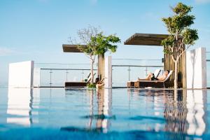 a swimming pool with two people laying on lounge chairs at ibis Styles Vung Tau in Vung Tau