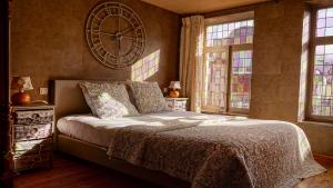 ein Schlafzimmer mit einem Bett mit einer großen Uhr an der Wand in der Unterkunft Gîtes d'Apothecarius entre Namur et Dinant in Fosses-La-Ville