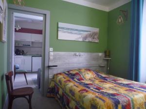 a bedroom with green walls and a bed and a kitchen at Au Relais du Parc de Millevaches in Felletin