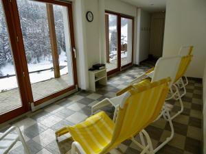 a living room with yellow chairs and windows at Chasa Vaidum in Samnaun