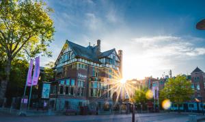 a large building with the sun shining on it at Hotel Alexander in Amsterdam