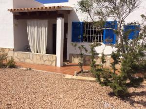 une maison avec volets bleus et terrasse couverte dans l'établissement VIVIENDAS ES CARNATGE, à Playa Migjorn