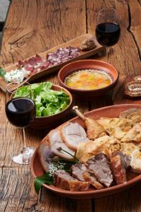 una mesa de madera con platos de comida y copas de vino en Tourist Farm Pri Martinovih en Krška Vas