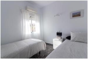 a white bedroom with a bed and a window at Apartamento en centro de Moraira in Moraira