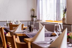 uma sala de jantar com mesas e cadeiras com copos de vinho em Hotel Casa Maria em Halblech