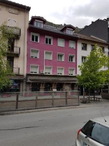 un bâtiment rose sur le côté d'une rue dans l'établissement studio 26 m2 tout équipé, à Modane