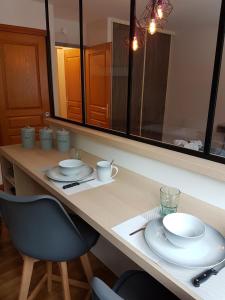 une table avec des assiettes, des tasses et une chaise dans l'établissement studio 26 m2 tout équipé, à Modane