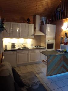 cocina con armarios blancos y encimera en chalet cathy, en Laveissière