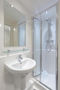 a white bathroom with a sink and a shower at ALTIDO Affordable Edinburgh - Adults only in Edinburgh
