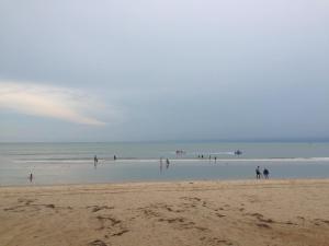 a group of people standing in the water on a beach at TK Guesthouse in Cha Am