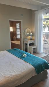 a bedroom with a bed with a blue blanket on it at Whales Way Ocean Retreat in Wilderness