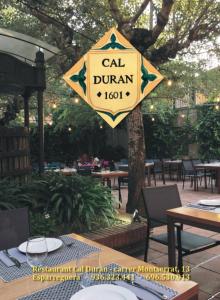 a sign for a cal dumani restaurant hanging from a tree at Cal Duran in Esparraguera