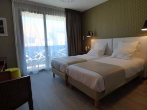 um quarto de hotel com duas camas e uma grande janela em Cit'Hotel Grand Hotel L'Etape em Saint-Flour