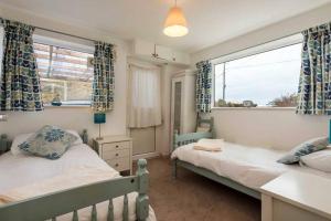 トレアルジルにあるSECLUDED COTTAGE-4 BED-Sleeps 8- TREARDDUR BAYのベッド2台と窓のある寝室