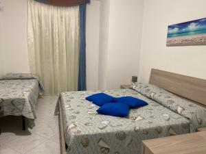 a bedroom with two beds with blue pillows on it at La Casa Gialla in Cala Gonone