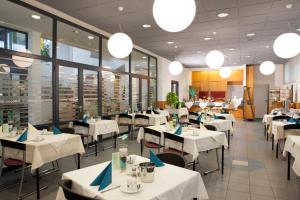 a restaurant with white tables and chairs and windows at Am Spiegeln dialog.hotel.wien in Vienna