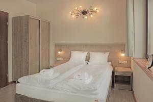 ロンデク・ズドルイにあるBursztynowe Bukiのベッドルーム1室(白い大型ベッド1台、タオル2枚付)