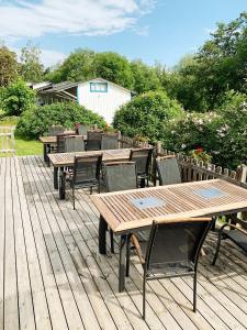 a row of wooden tables with chairs and umbrellas at Övernäsgården Gästhem in Mariehamn