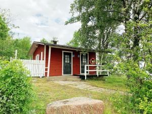 a small red house with a white fence at Övernäsgården Gästhem in Mariehamn